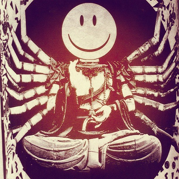 A collage caricature of a many-armed Hindu-style deity with the classic graphic smiley face for a head