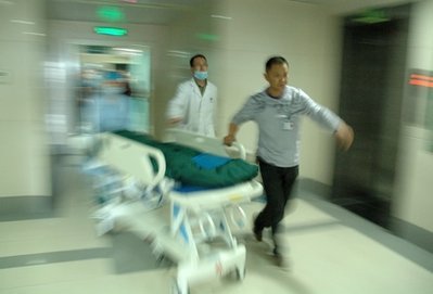 Two Asian male doctors quickly wheeling a stretcher in a hospital
