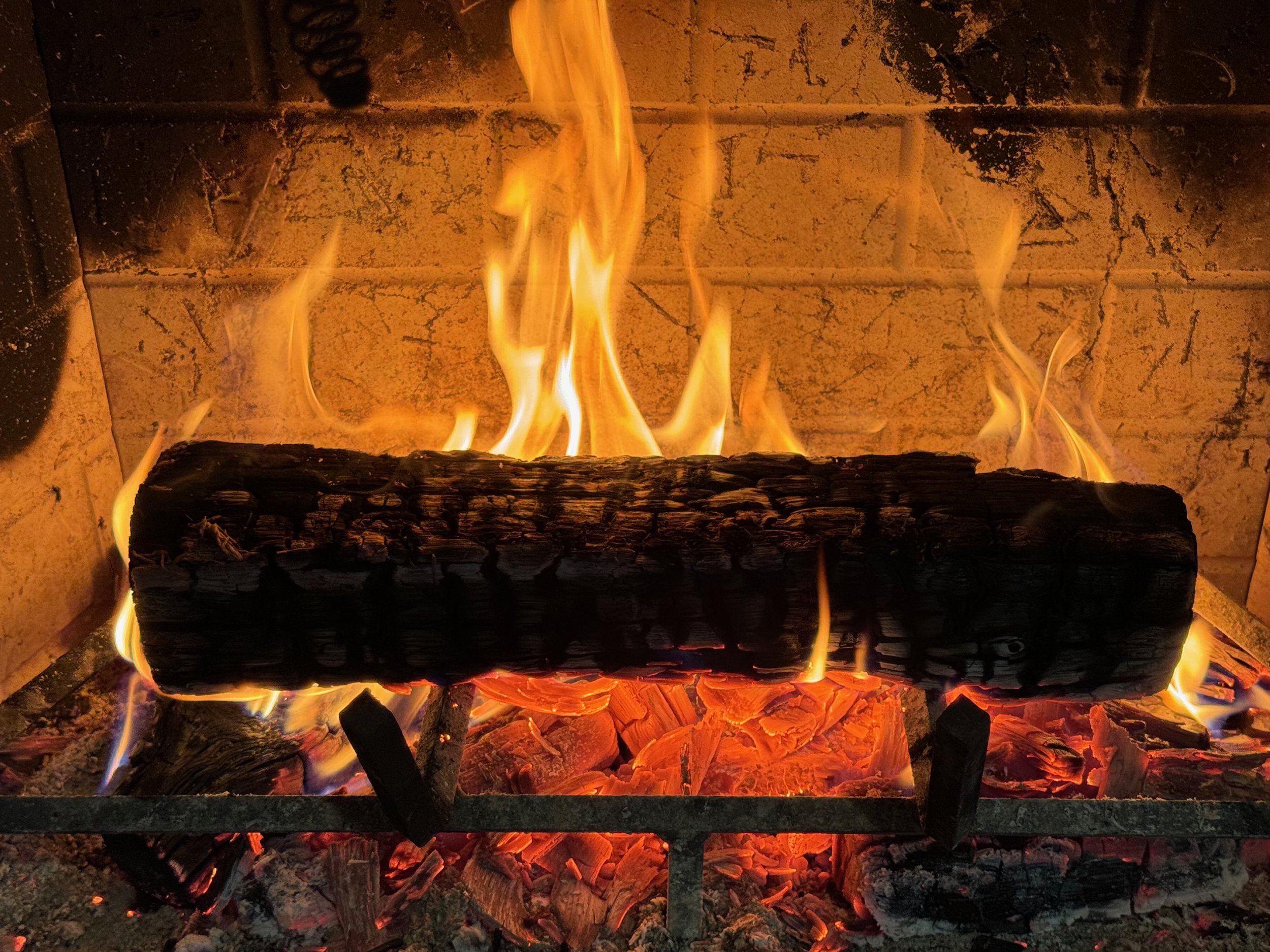 A one-log fire in a fireplace with a hot bed of coals underneath