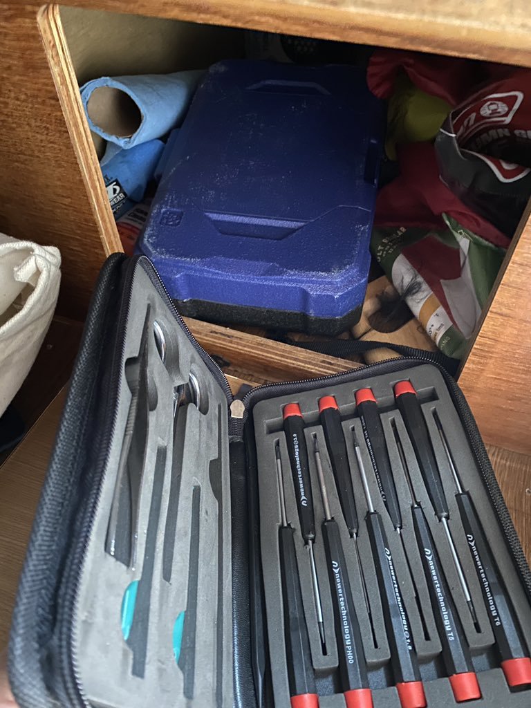 A photo of a screwdriver set being removed from a storage cubby in a sleeper van.